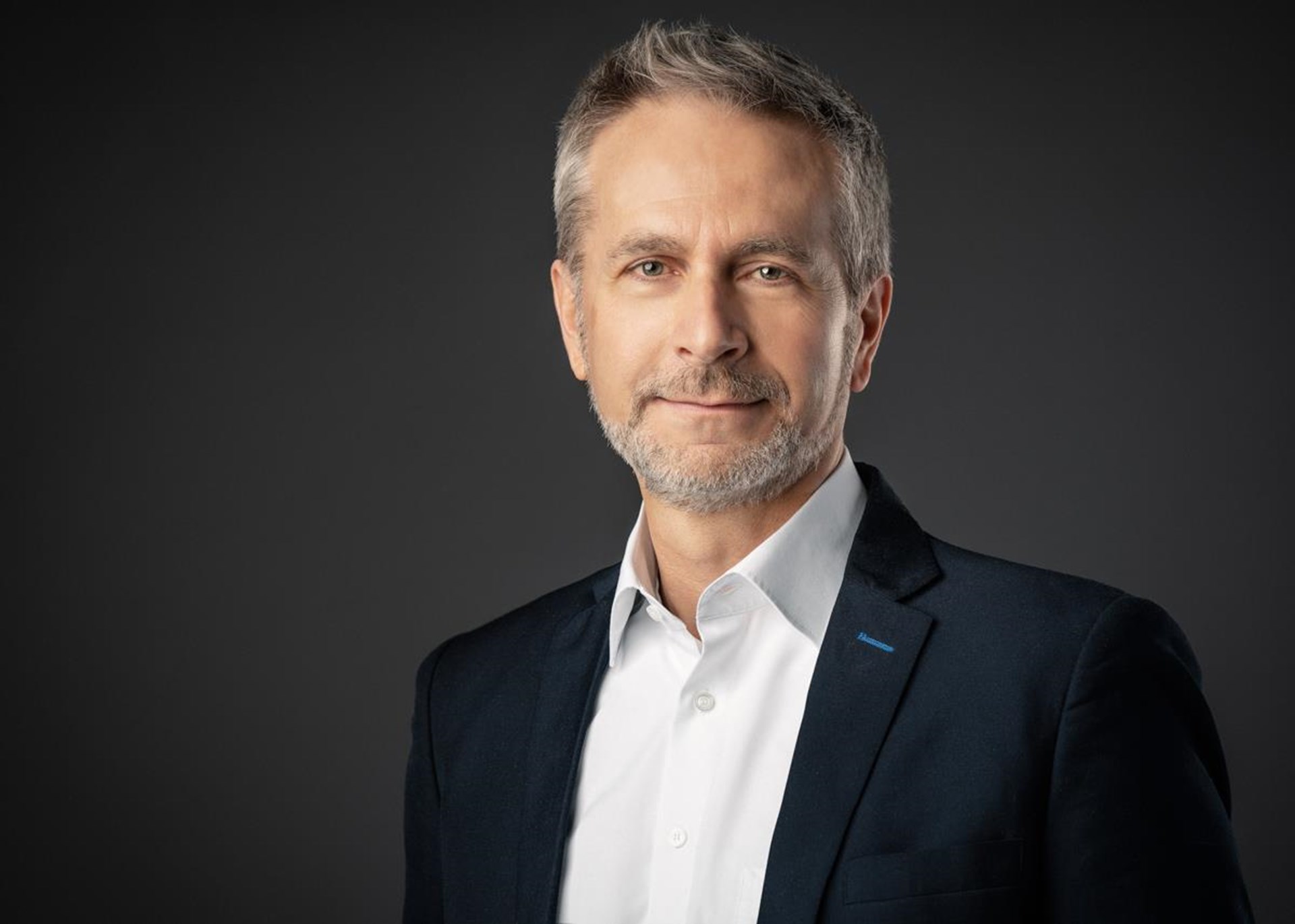 Portrait eines Mannes in schwarzem Anzug und weißem Hemd.